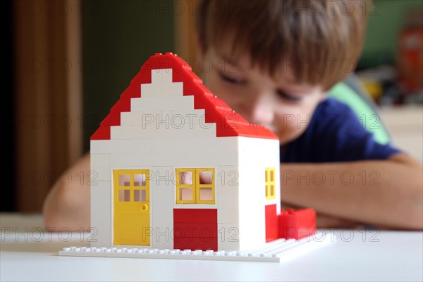 Symbolic image: Boy builds a house with building blocks