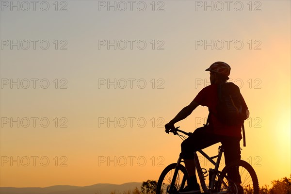 Symbolic image: Silhouette of a mountain biker on a warm summer evening