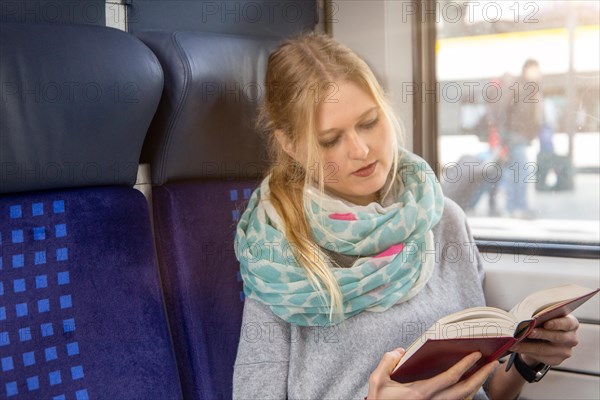 Young woman reading a book on the train