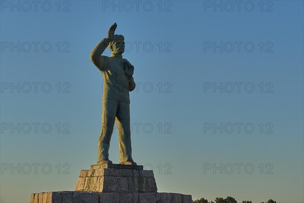 Statue of a man with his arm outstretched towards the sky at dawn, bronze statue of a waving sailor in memory of the souls lost at sea, Gythio, Mani, Peloponnese, Greece, Europe