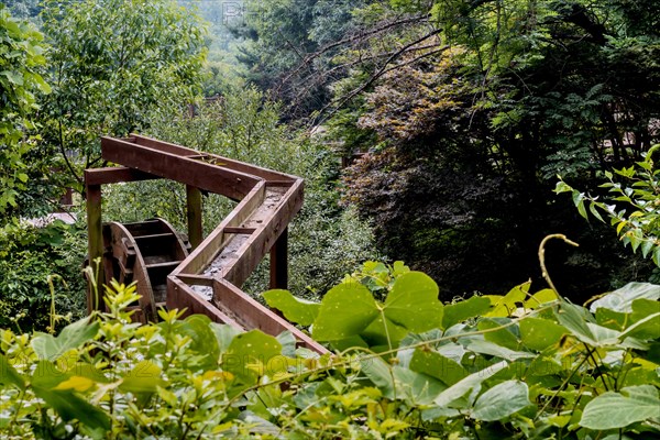 Wooden water trough and waterwheel in lush mountain recreational park in South Korea