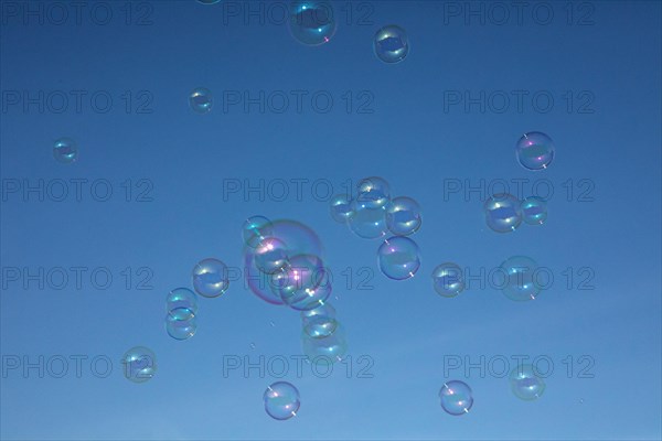Soap bubbles multicoloured film of soapy water next to each other in front of a blue sky