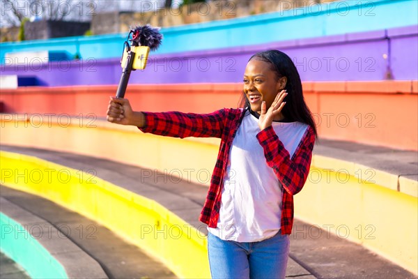 African woman content creator recording a live video in social media in a colorful park