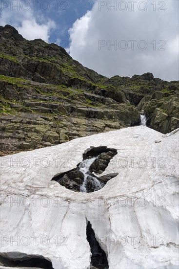 Snow-covered mountain landscape with rocks and a stream under a cloudy sky, small Capra waterfall, Transfogarasan High Road, Transfagarasan, TransfagaraÈ™an, FagaraÈ™ Mountains, Fagaras, Transylvania, Transylvania, Transylvania, Ardeal, Transilvania, Carpathians, Romania, Europe