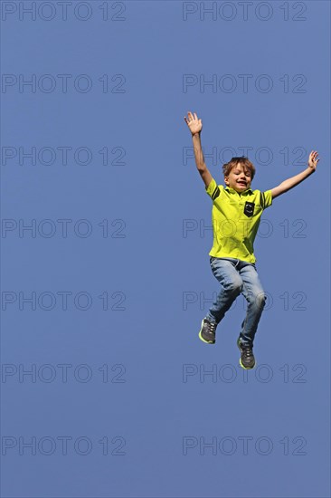 Symbolic image: Boy jumping into the air, blue sky in the background