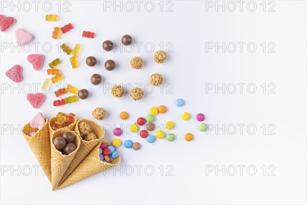 Various sweets in and out of ice-cream cones on a white background, copy room