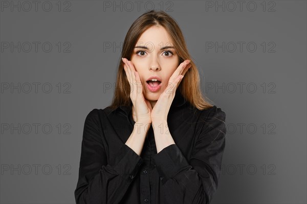 Studio portrait of excited young woman on grey background