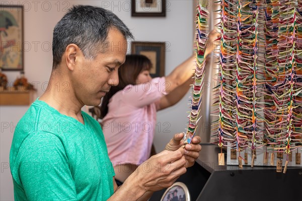 Japanese man holding a paper crane. Memories in the family home