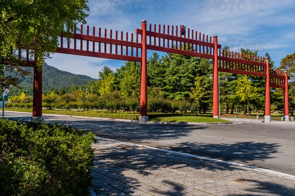 Large red wooden gate across four lane road in public park in South Korea