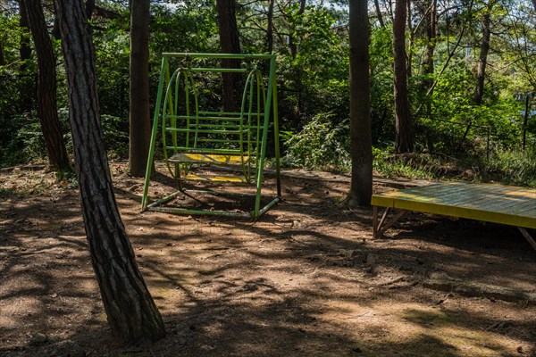 Metal swing bench under trees in shaded roadside park in South Korea
