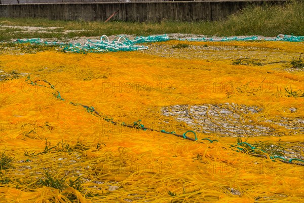 Closeup of large yellow fishing nets with yellow floats laid out on ground to dry in South Korea