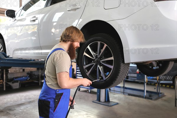 Symbolic image: Car workshop: Car mechatronics technician servicing tyres