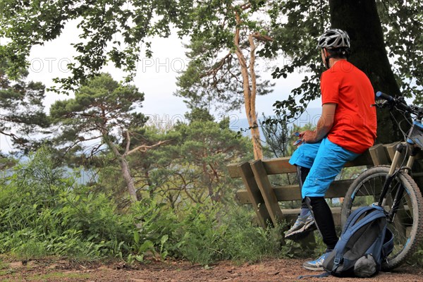 Mountain biker taking a break on a bench in the Palatinate Forest near the Weinbiet above Neustadt an der Weinstrasse