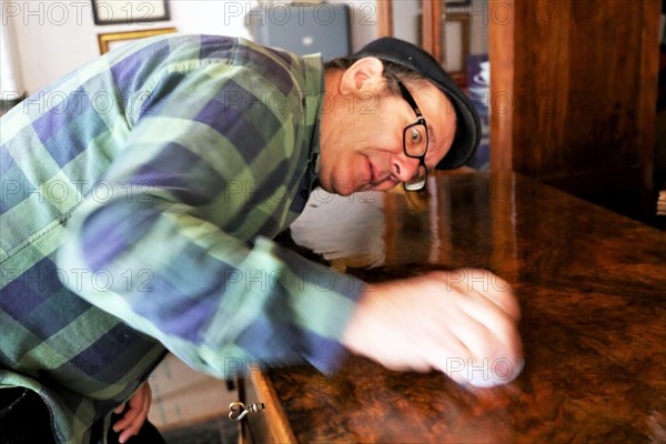 Furniture restorer polishes a table