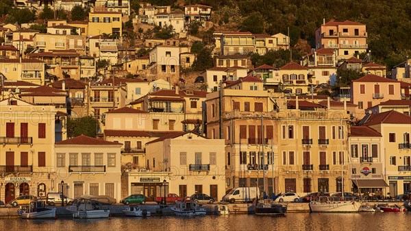 The warm colours of the evening sun shine on the traditional buildings and boats on the coast, Gythio, Mani, Peloponnese, Greece, Europe