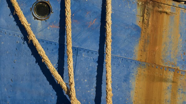 Detailed view of the side of a blue ship with ropes and rusty patches, Gythio, Mani, Peloponnese, Greece, Europe