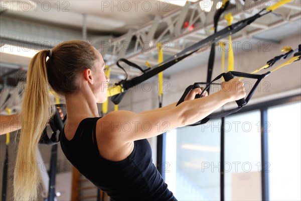 Young woman doing TRX training in the gym, (Neuhofen, Rhineland-Palatinate)