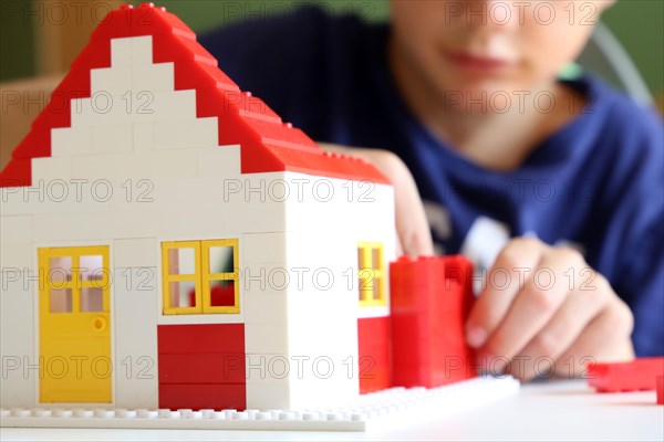 Symbolic image: Boy builds a house with building blocks