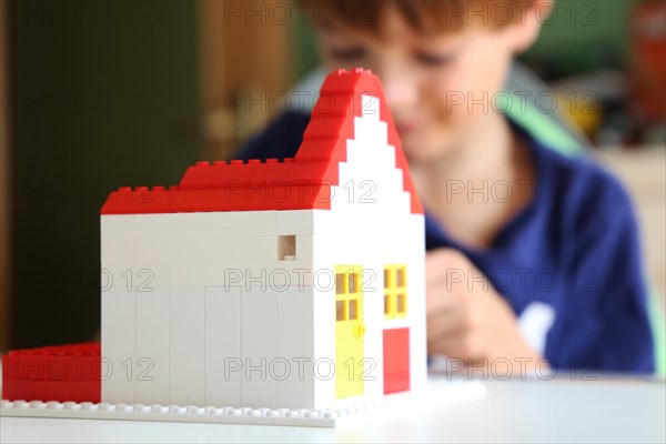 Symbolic image: Boy builds a house with building blocks