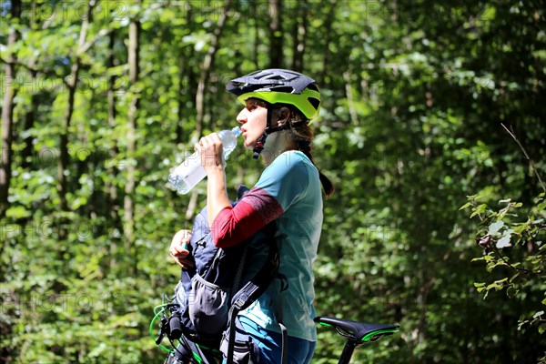 Symbolic image for drinking enough during sport: mountain biker quenches her thirst