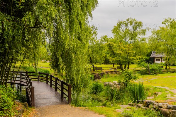 Peaceful landscape of wooden footbridge and benches in a public park on an overcast rainy morning in South Korea