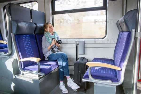 Young woman on a train holding a professional camera