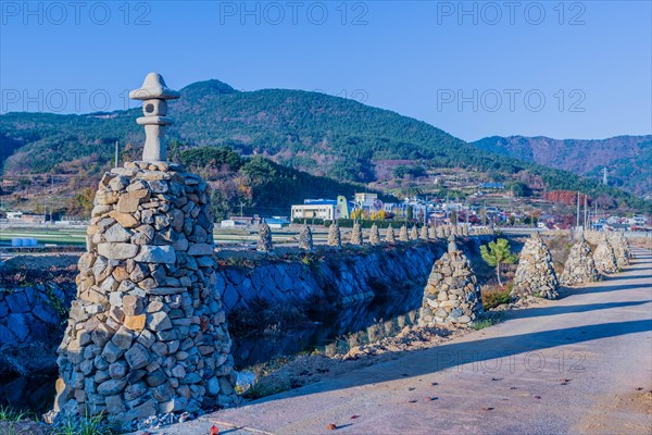 Row of cairn beside single lane concrete road in rural community in South Korea