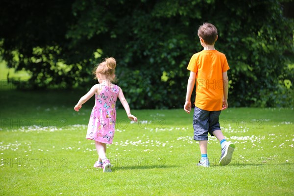 Boy and girl (siblings) running in a meadow