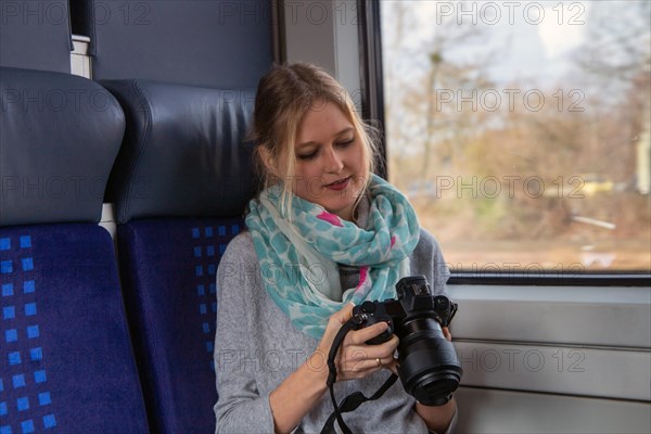 Young woman on a train holding a professional camera hand