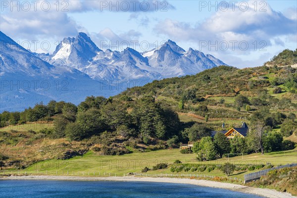 House on the coast of the Beagle Channel, behind the mountains of Hoste Island, Ushuaia, Tierra del Fuego Island, Patagonia, Argentina, South America