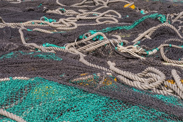 Closeup of large black and green fishing nets with yellow floats laid out on ground to dry in South Korea