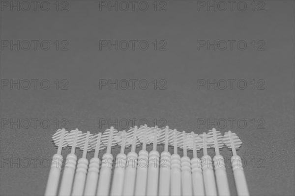 Black and white of plastic flossing picks on gray background