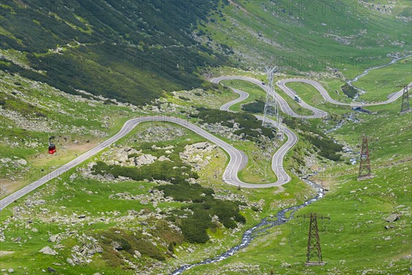 A serpentine road winds through the mountain landscape with views of electricity pylons, Balea River, mountain road, Transfogarasan High Road, Transfagarasan, TransfagaraÈ™an, FagaraÈ™ Mountains, Fagaras, Transylvania, Transylvania, Transylvania, Ardeal, Transylvania, Carpathians, Romania, Europe