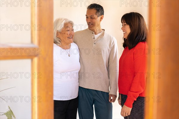 Mother and adult children of Japanese origin chatting animatedly in the entrance hall