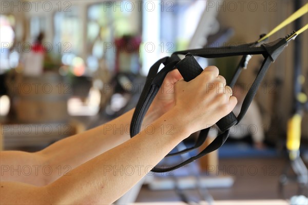 Young woman doing TRX training in the gym, (Neuhofen, Rhineland-Palatinate)