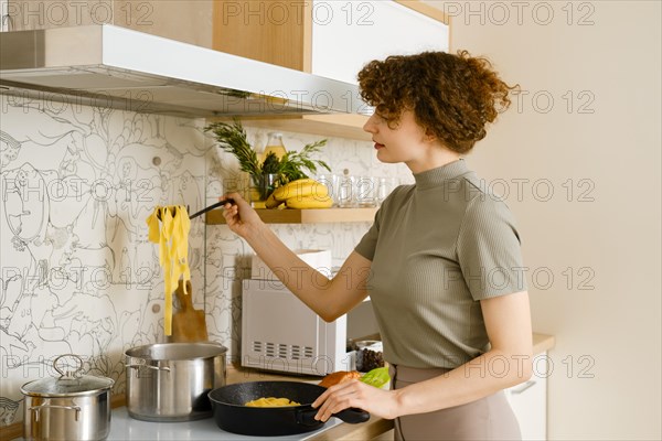 A woman takes out cooked pasta from a pot of water