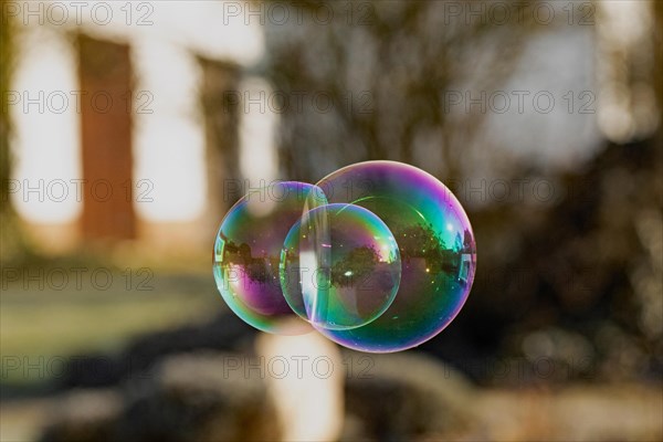 Soap bubbles three-coloured film of soapy water next to each other with mirror image in front of building