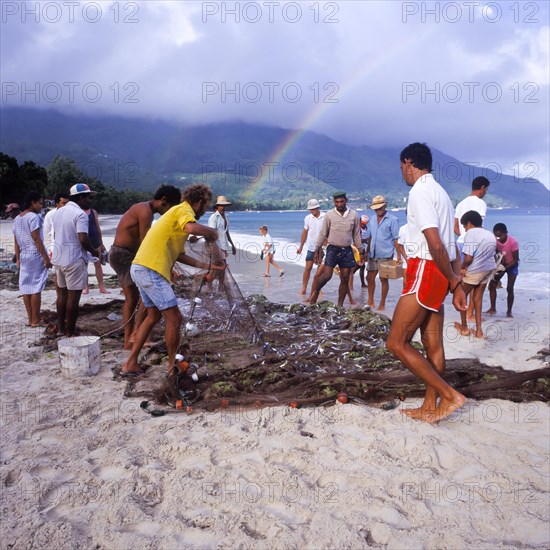 Seychelles, Mahe, Beau Vallon, fishermen pull fishing net ashore, Africa