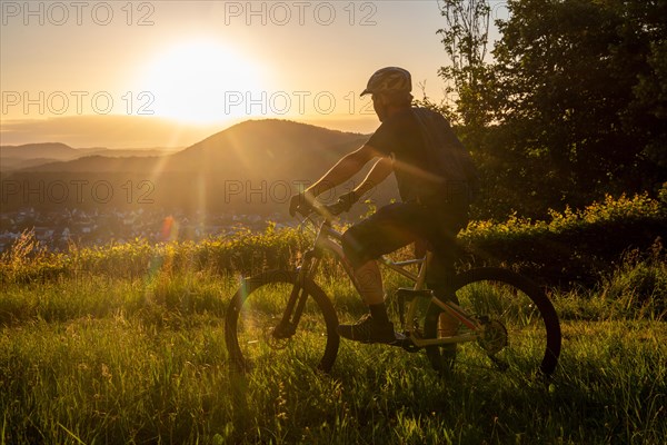Mountain biker in the low evening sun looking towards the small town of Dahn in the Palatinate Forest