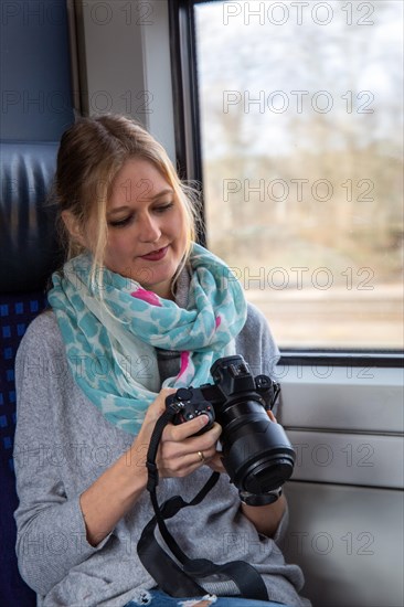 Young woman on a train holding a professional camera hand