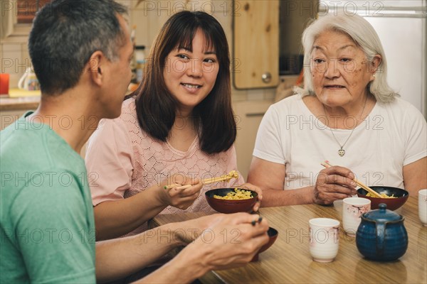 Elderly Japanese Mother with adult children having lunch at home. Concept of family, tradition and ethnic diversity