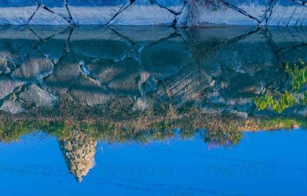 Rock cairn on edge of canal reflected in calm blue water in South Korea