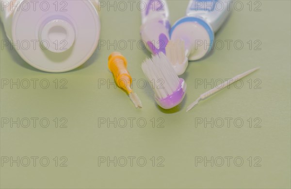 Closeup of toothbrushes and flossing picks next to opened tube of toothpaste