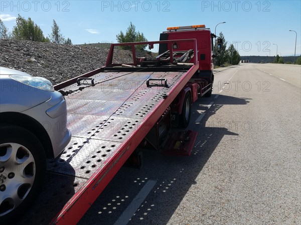 Detail of a tow truck towing a damaged car in the middle of the street