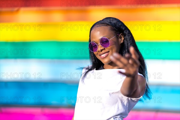 African woman inviting to come with hand and smiling next to a striped colorful stairs