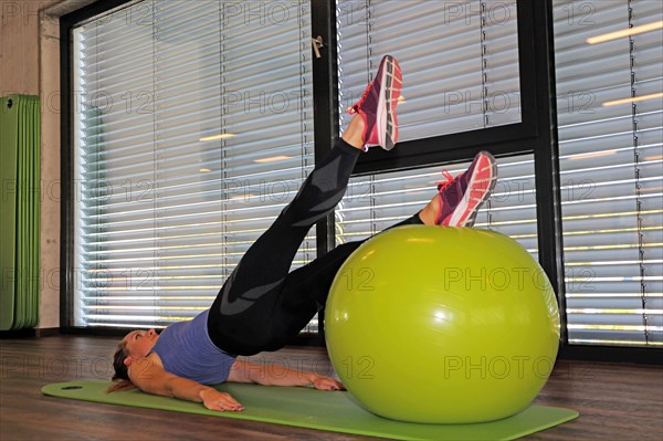 Symbolic image: Young woman doing exercises on an exercise ball