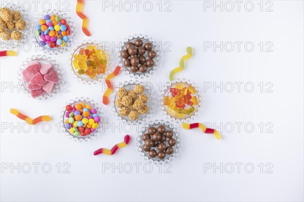 Sweets on and next to small glass plates on a white background photographed from above