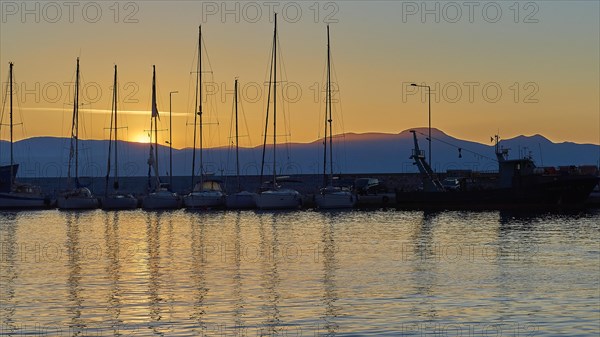 Yachts in the harbour at sunset with mountains in the background and evening sky, Gythio, Mani, Peloponnese, Greece, Europe