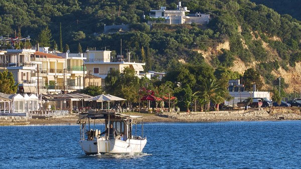 Fishing boat on an idyllic Mediterranean coast with town and hills in the background, Gythio, Mani, Peloponnese, Greece, Europe