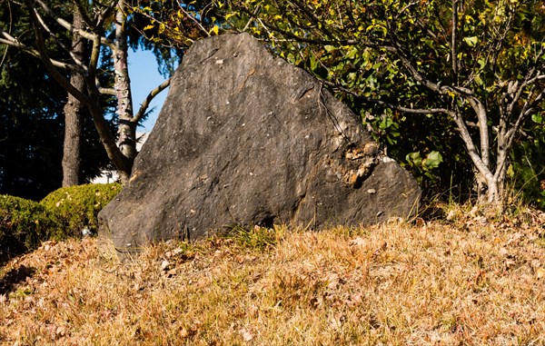 Large triangular boulder on side of hill covered with brown autumn grass